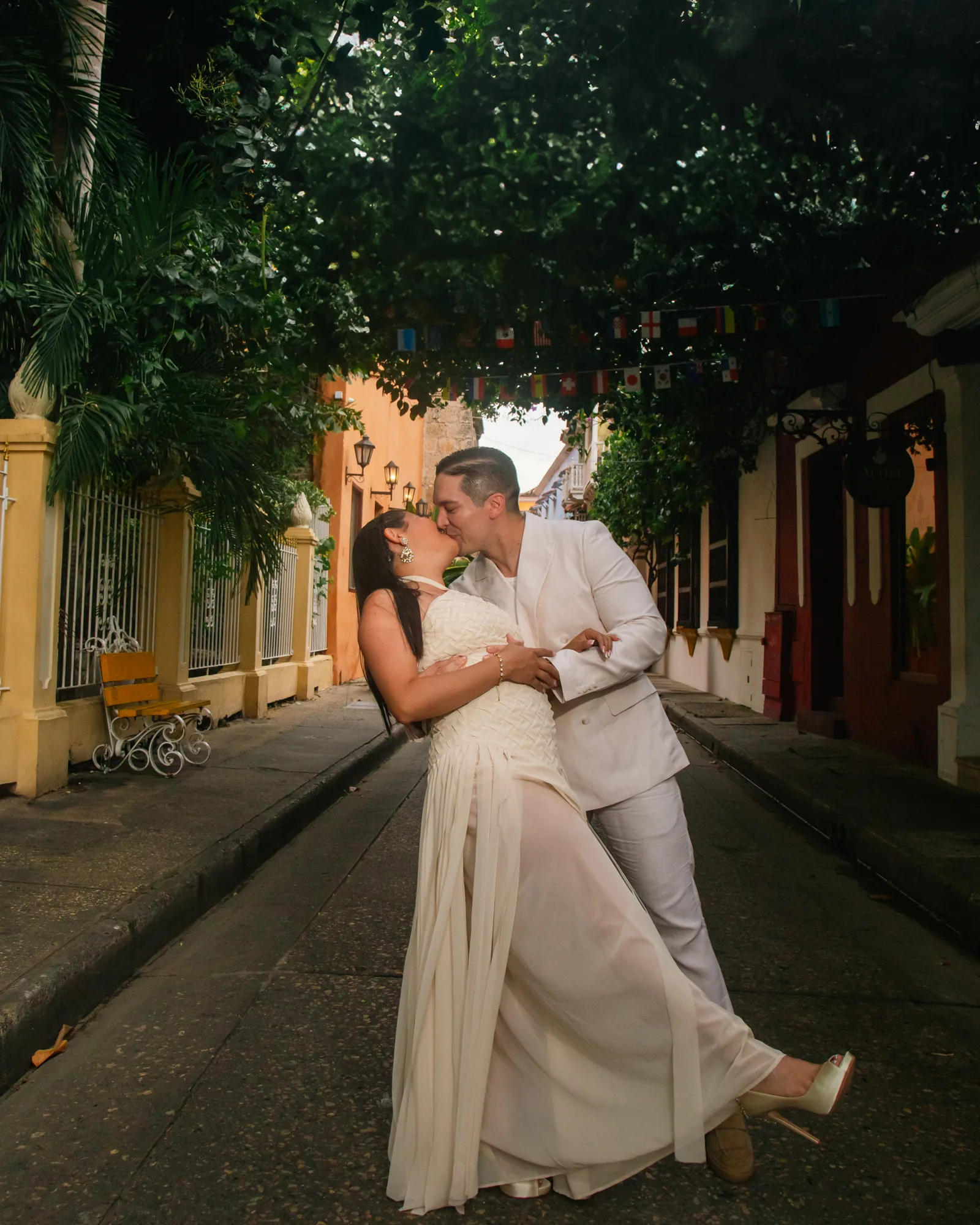 Fotos preboda en Cartagena, beso de novios en calle colonial bajo los árboles